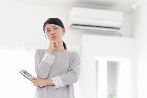 エアコンの前で困っている女性の写真