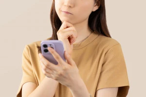 スマホを見て考える女性の写真