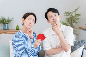 財布を持って悩んでいる夫婦の写真