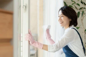 窓掃除をする女性のハウスクリーニング業者の写真
