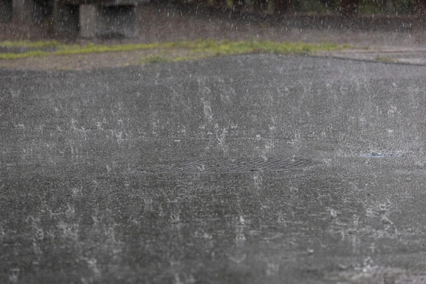アスファルトに打ち付ける雨粒の写真