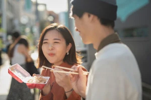 食べ歩きをする笑顔のカップルの写真