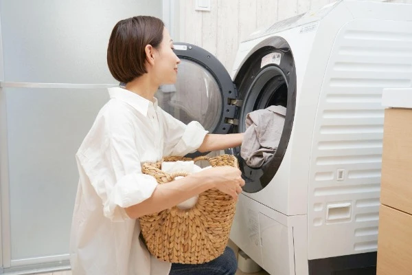 洗濯機で衣類を出し入れする女性の画像