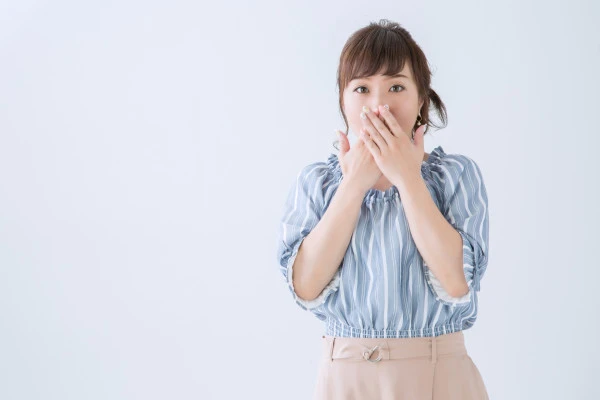 口元に手を当てて声を出さないようにしている女性の写真