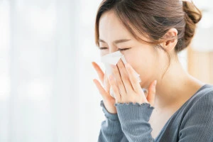 アレルギーでくしゃみをする女性の写真