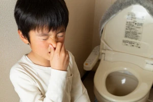 トイレからのにおいで鼻をつまんでいる子供の写真