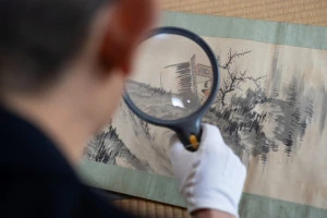 古い掛け軸の鑑定をしている男性の写真