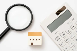 ルーペと家の模型と電卓の画像