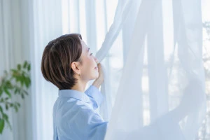 窓を開けて風通しを良くしようとしている女性の写真