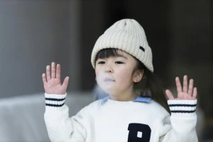 子供が窓に手をあてて息を吹きかけている写真