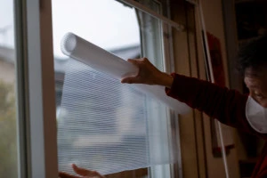 窓ガラスに断熱シートを貼る男性の写真