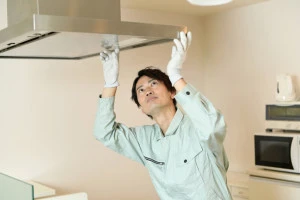 キッチンで換気扇を確認する男性作業員の写真
