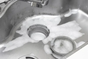 台所の流し台を泡の洗剤で掃除するイメージ