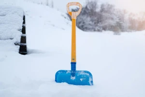 雪が積もった地面に刺さったシャベルの写真