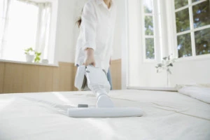 布団クリーナーをかける女性の写真