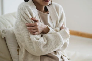 部屋の中で寒さを感じる女性の写真