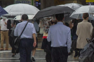 雨のなか行き交う通勤者たちの風景