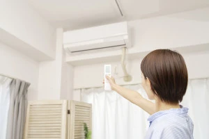 エアコンのリモコンを持つ女性の写真