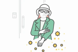 玄関で服についた花粉を払う女性のイメージ