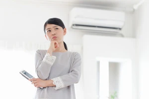 エアコンの前で困る女性の写真