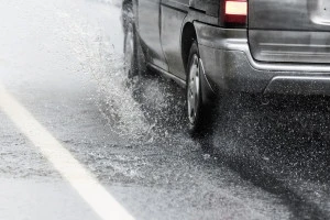 大雨の中道路を走る車の写真