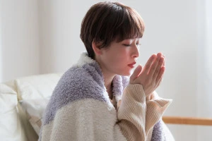 部屋で寒がる女性の写真