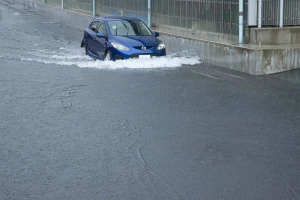 冠水した道路を走る車の写真