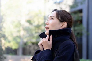 寒くてコートの襟をたてる女性の写真