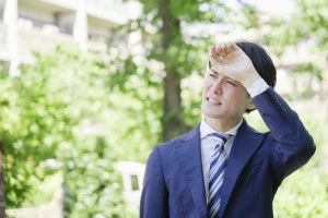 暑がるスーツ姿の男性の写真