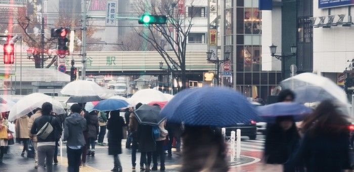 雨の日の渋谷駅前と傘をさして歩く人々