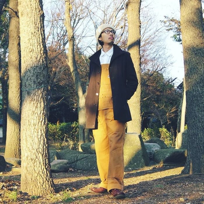 白シャツにオーバーオールを合わせたコーデをした男性の写真