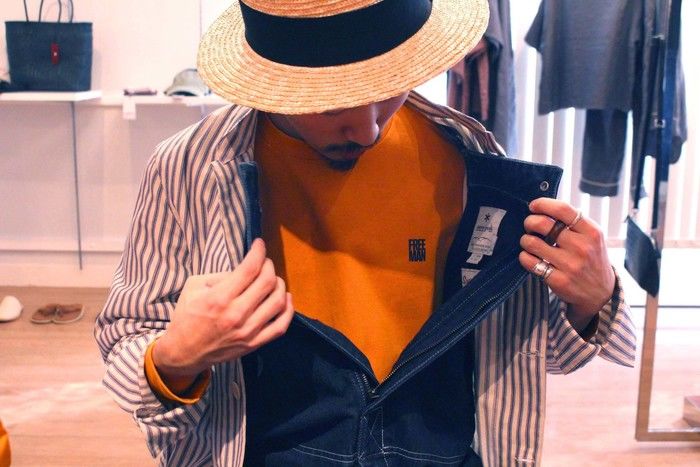 ボタンを外したオーバーオールを脱ごうとしている男性の写真
