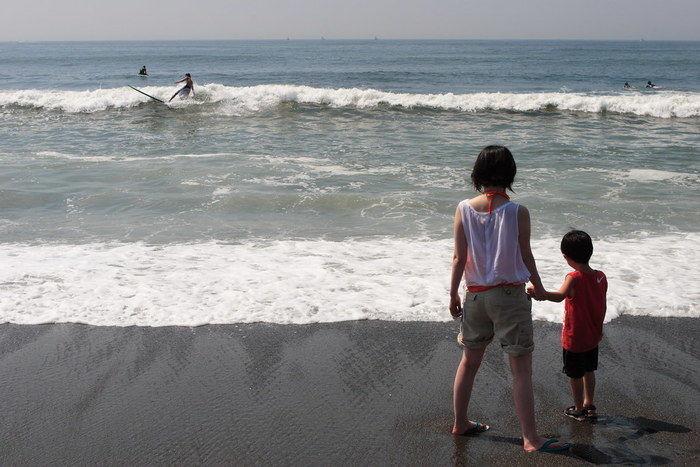 海沿いで海を眺める兄妹の写真