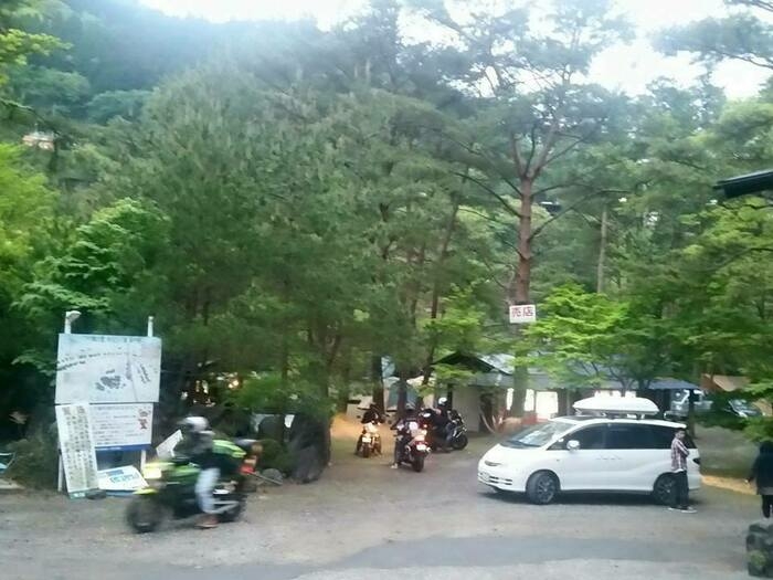 木立と3~4台のバイクと白い車