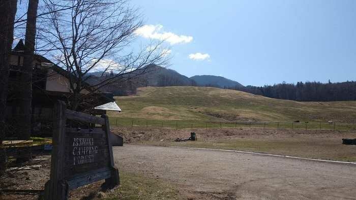左にログハウスと看板、正面奥になだらかな斜面