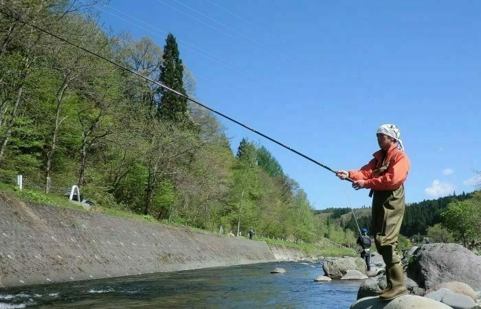 道路わきの川で釣りをする男性