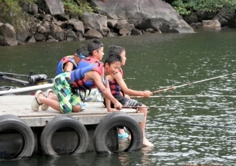 ライフジャケット着用で桟橋で釣りをする4人の男の子