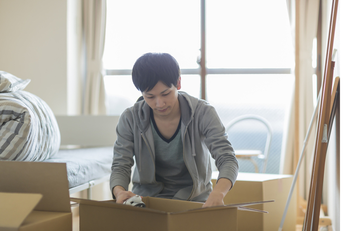 段ボールに荷物を詰める男性