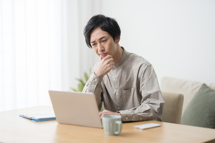 PC画面を見つめて困っている男性