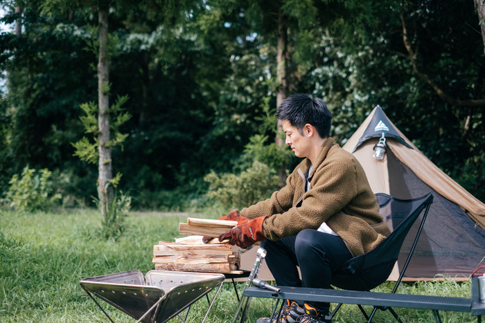 薪を焚き火台へ入れようとしている男性
