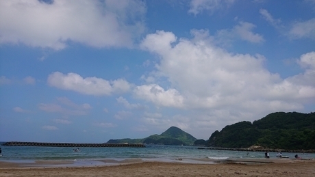 青い空の下に広がる海と向こうに山