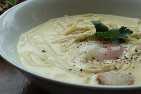 白い食器に盛られたホワイトクリームスープパスタに温泉卵がのっている