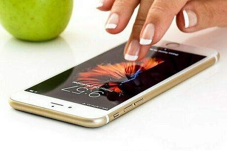 デスクの置いたスマホを操作するネイルが施された指先