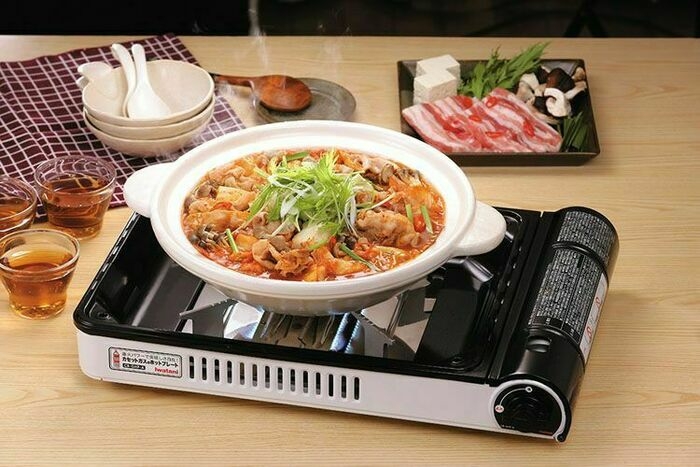 具材の入った土鍋がカセットコンロにかけられているテーブルの上にはグラスや食器