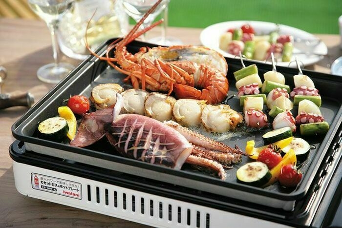 屋外でホットプレートで魚介や野菜を焼いている