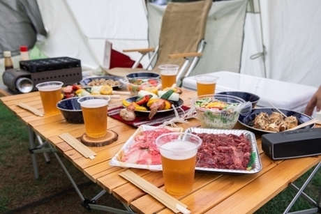 屋外のテーブルに焼肉具材やビールが入ったコップ