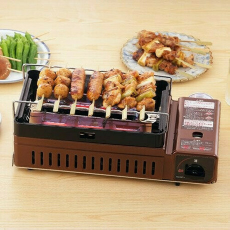 茶色いカセットコンロで焼き鳥を焼いている