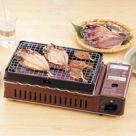 テーブル上のカセットコンロで魚のを網焼きしている