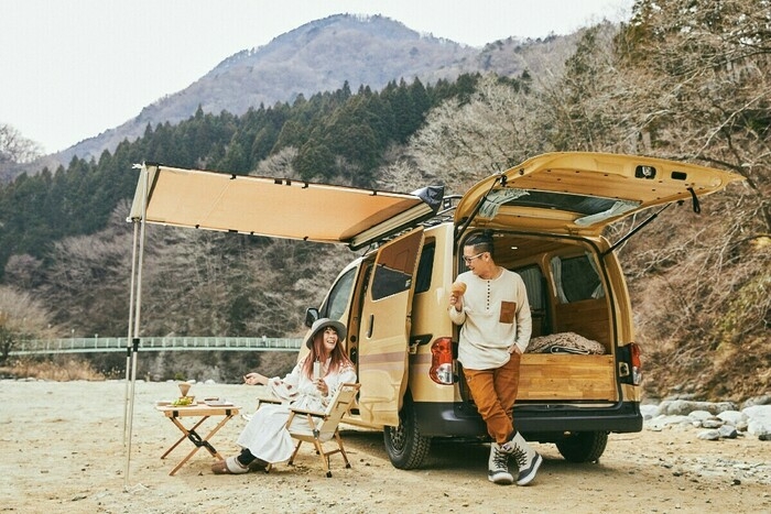 サイドシェルターを広げ、車でキャンプを楽しむ2人