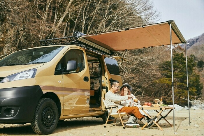 車の傍らでキャンプを楽しむ夫婦